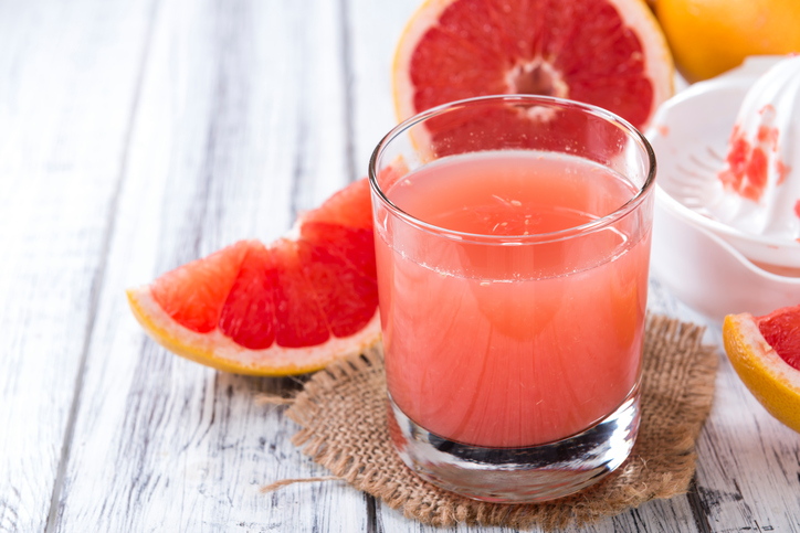 Pure Grapefruit Juice (close-up shot) on rustic wooden background