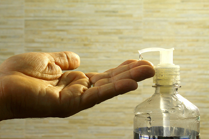 Hand getting a pump of hand sanitizer from bottle