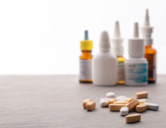 Nasal sprays in the background with various pills sitting in front.