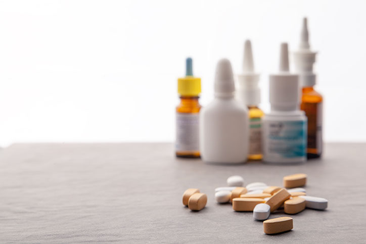 Nasal sprays in the background with various pills sitting in front.