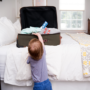 Child reaching into an open suitcase on the bed that contains medicines