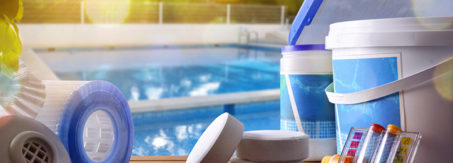 Swimming pool service and equipment with chemical cleaning products and tools on wood table and pool background. Horizontal composition. Front view