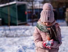 Young girl outside in the snow holding a pile of snow