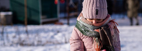 Young girl outside in the snow holding a pile of snow