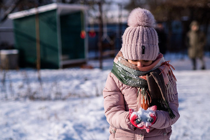 Young girl outside in the snow holding a pile of snow