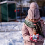 Young girl outside in the snow holding a pile of snow