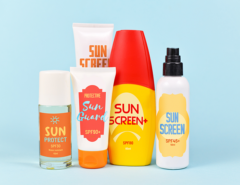 Different protective sun screen cream bottles and spray tubes with made up labels on light blue background