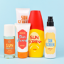 Different protective sun screen cream bottles and spray tubes with made up labels on light blue background