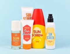 Different protective sun screen cream bottles and spray tubes with made up labels on light blue background