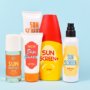 Different protective sun screen cream bottles and spray tubes with made up labels on light blue background