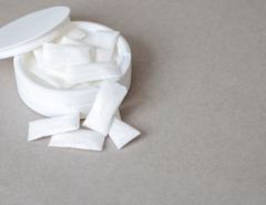 white container with nicotine pouches on plain grey surface