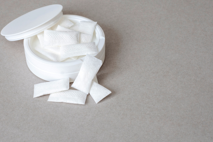 white container with nicotine pouches on plain grey surface