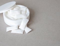 white container with nicotine pouches on plain grey surface