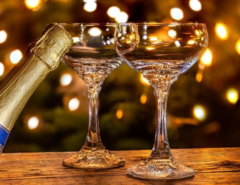 Two glasses and a champagne bottle with Christmas lights in the background
