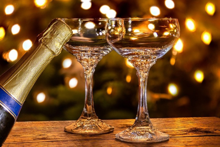 Two glasses and a champagne bottle with Christmas lights in the background