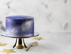 Cake with a metallic purple and blue finish sits on a cake stand.